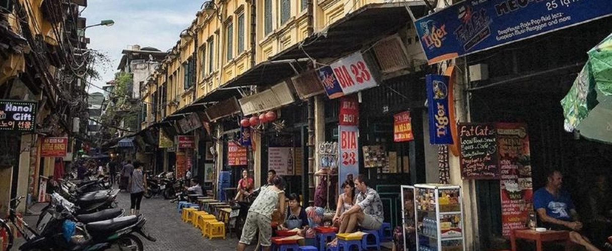Busy shopfronts and motorbikes along a street in the Hanoi Old Quarter