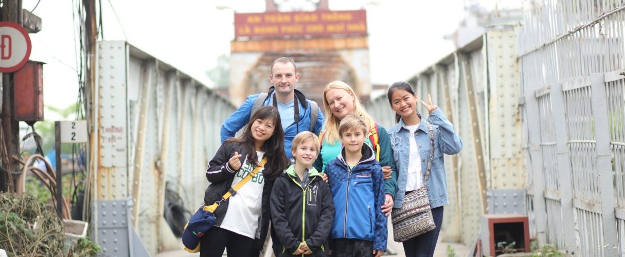 Group of travellers and their student guides posing together on a Hanoi street