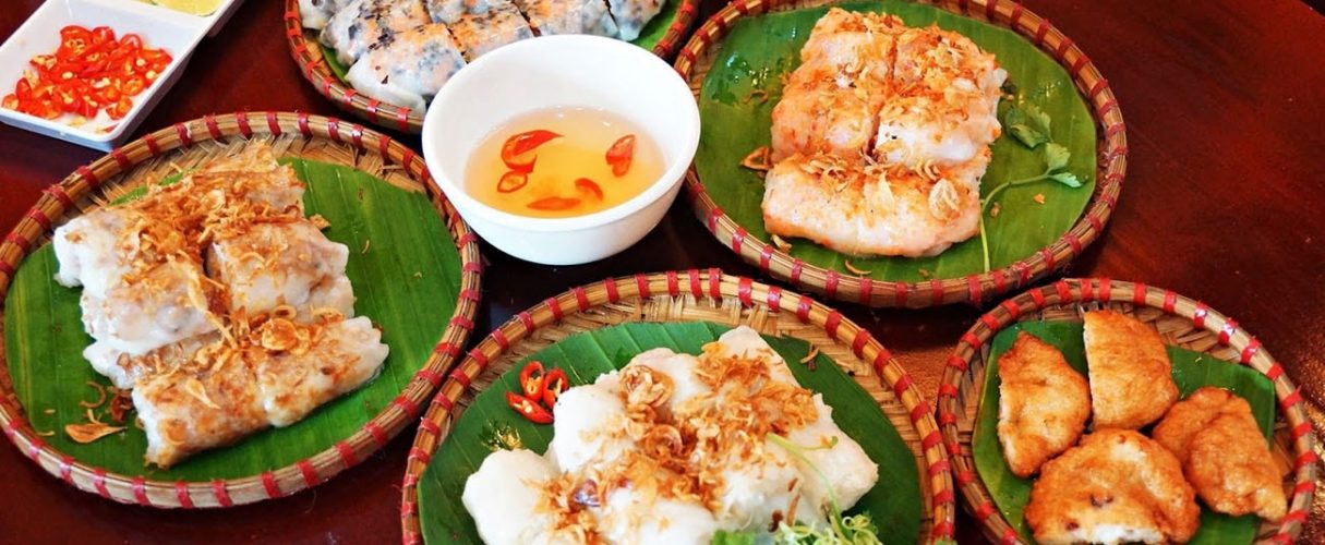 Plates of banh cuon and banh tom on banana leaf with a bowl of dipping sauce