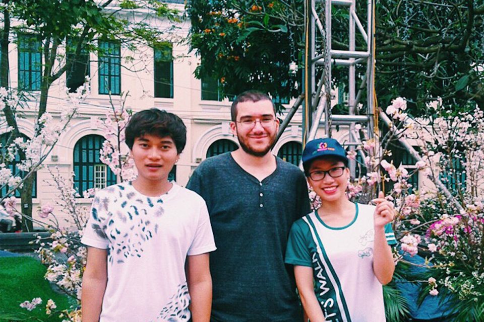Travellers and their student guide in front of a pink colonial building in Hanoi