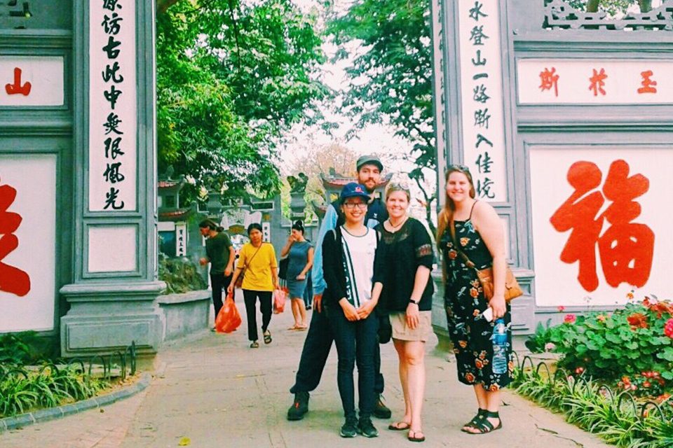 Travellers posing beside red calligraphy panels at a historic site in Hanoi