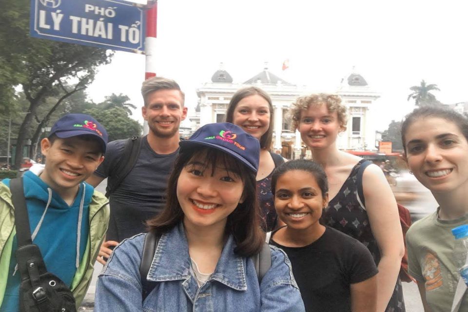 Group selfie of travellers and guides beside the Ly Thai To street sign in Hanoi