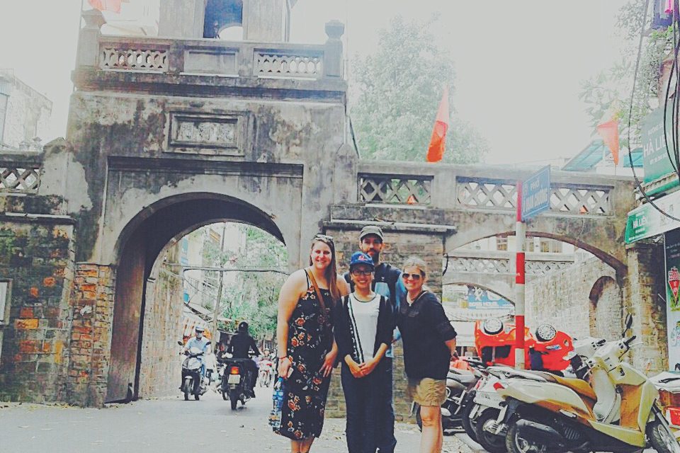 Travellers under the old Quan Chuong gate of the Hanoi Old Quarter as motorbikes pass