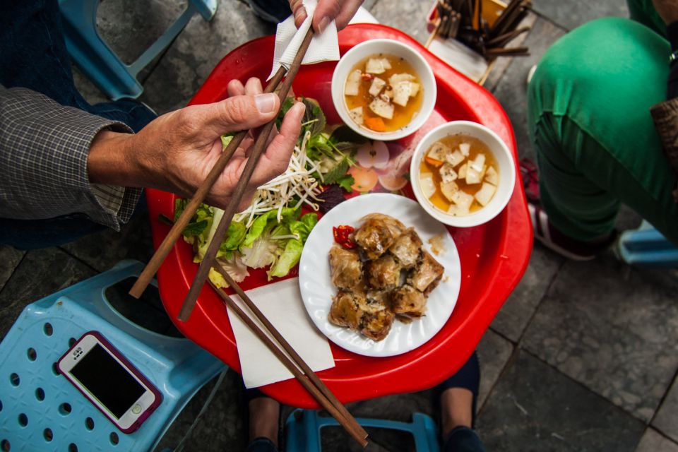 Overhead view of a red plastic street table with bun cha, herbs and chopsticks